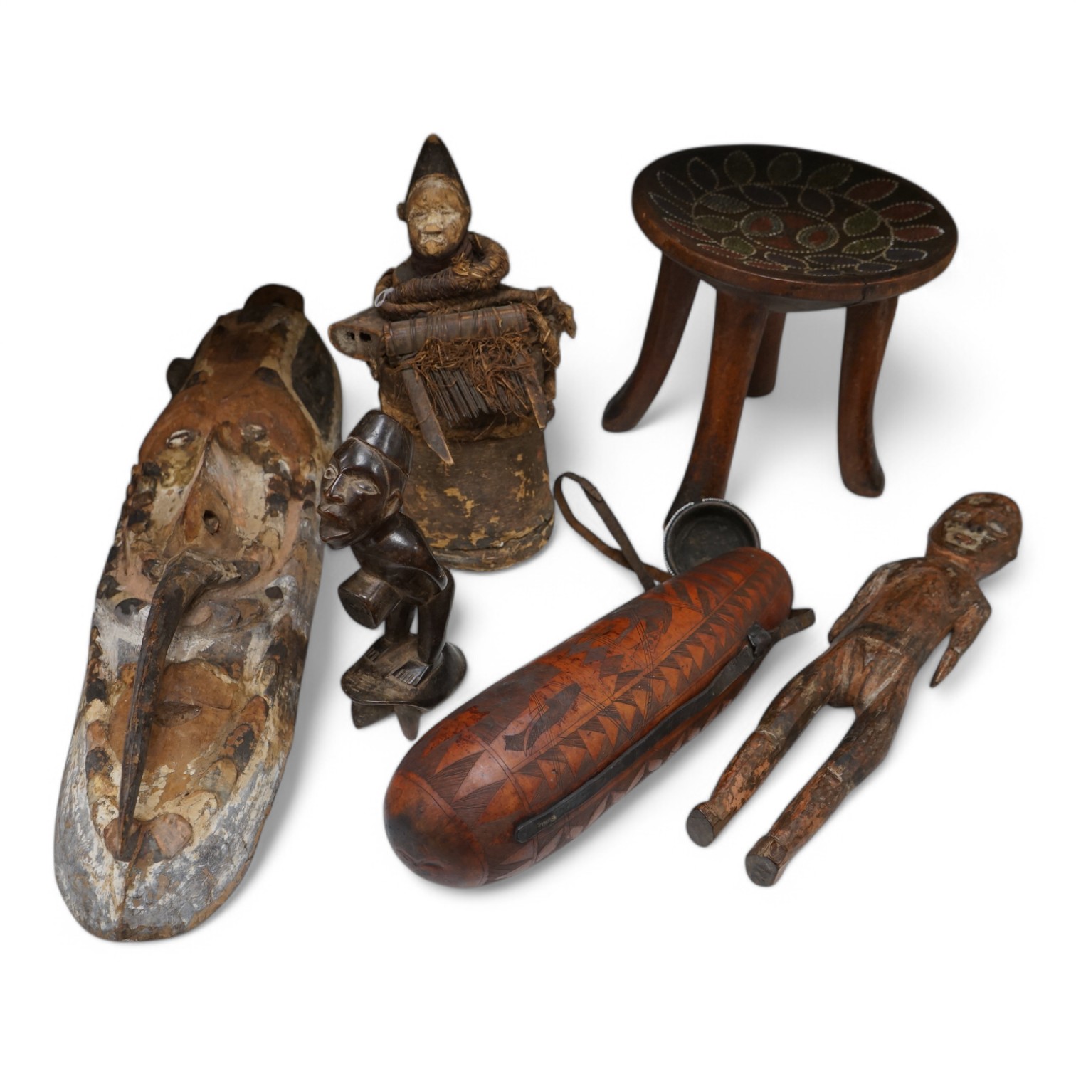 A group of African tribal artefacts, including a stool, a large painted carved mask, a carved gourd container and three carved figures, mask 76cm high. Condition- fair to good